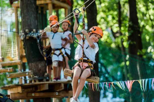 selective focus of kid riding on cable car near multicultural friends