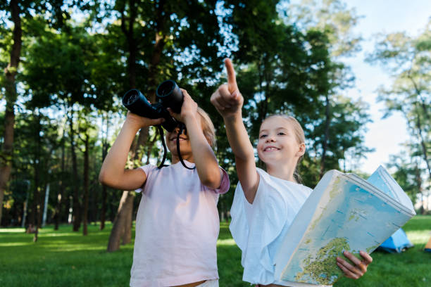istock cute kid holding map and pointing with finger near friend looking through binoculars 1179612552