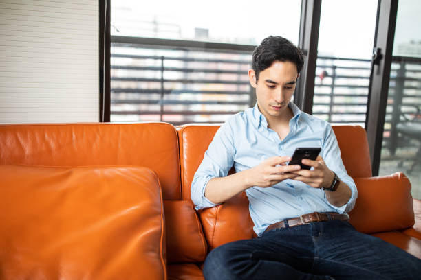 istock Asian man relaxing alone in his apartment and text messaging 1179613055