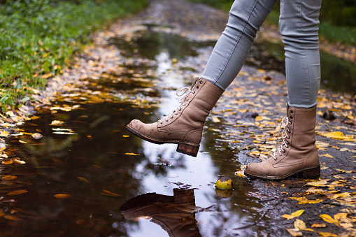 Hiking boot at autumn season. Woman walking on wet footpath after rain
