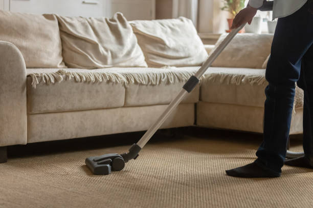 istock African american guy using vacuum cleaner, cleaning whitish carpet. 1179614220