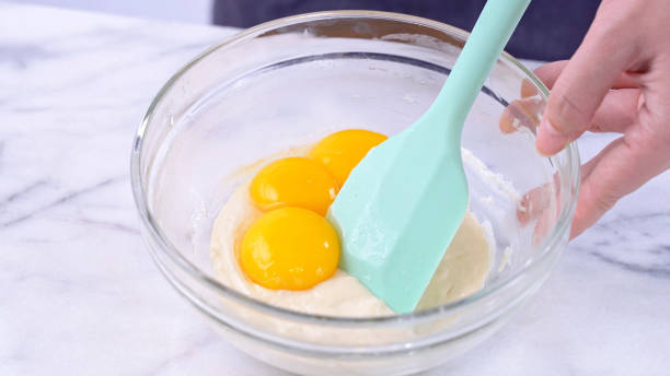 istock Mixing egg yolk into cake batter with green rubber spatula mixer tool stirring until smooth and blend well in a glass bowl. 1179617455