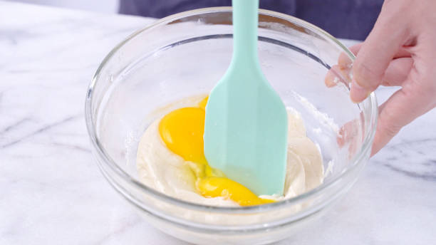 istock Mixing egg yolk into cake batter with green rubber spatula mixer tool stirring until smooth and blend well in a glass bowl. 1179617474
