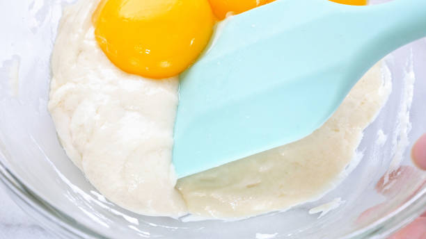 istock Mixing egg yolk into cake batter with green rubber spatula mixer tool stirring until smooth and blend well in a glass bowl. 1179617525