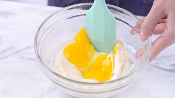 istock Mixing egg yolk into cake batter with green rubber spatula mixer tool stirring until smooth and blend well in a glass bowl. 1179617538