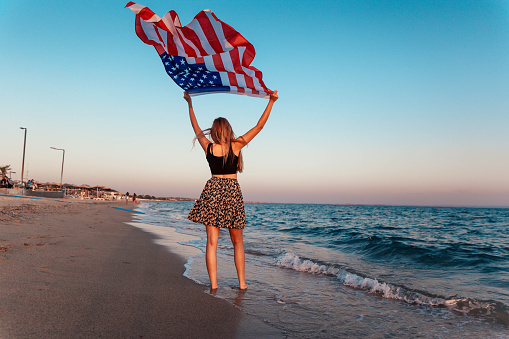 Young woman with American flag on the beach