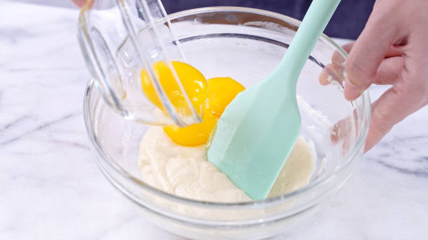 istock Mixing egg yolk into cake batter with green rubber spatula mixer tool stirring until smooth and blend well in a glass bowl. 1179618493