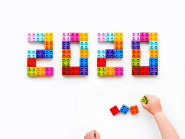 istock New 2020 Year. Child is playing with colorful constructor blocks. Kid's hands with bricks toy on white background. Educational toy, flat lay, top view. 1179618589