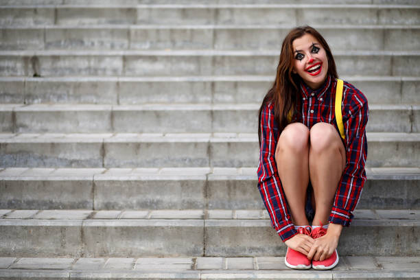 Cute girl in a clown makeup on a background of a fair and steps