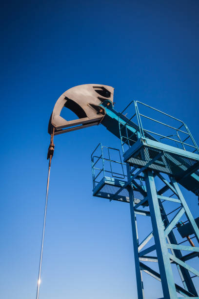 pompe à huile sur le fond du ciel bleu et du soleil de matin, l'éblouissser de soleil sur la pompe à huile - oil pump flash photos et images de collection