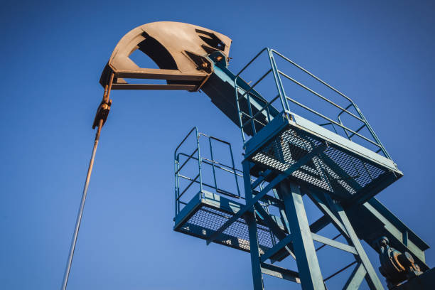 pompe à huile sur le fond du ciel bleu et du soleil de matin, l'éblouissser de soleil sur la pompe à huile - oil pump flash photos et images de collection