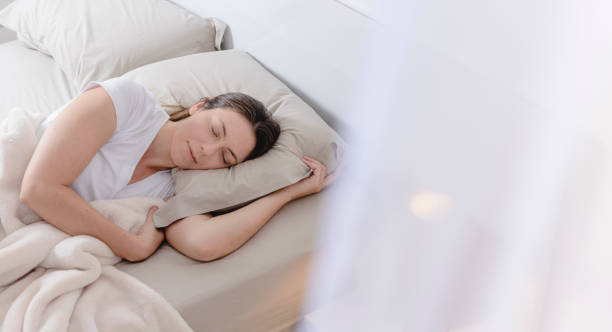 istock Beautiful woman lying on her side in bed with lamp on 1179622529