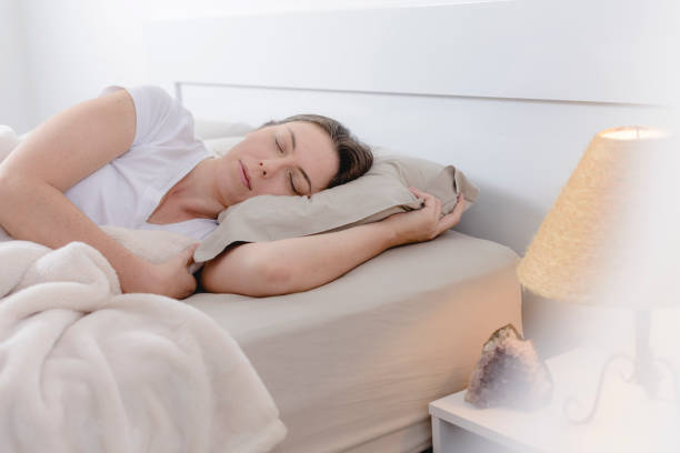istock Woman lying in bed sleeping with lamp on 1179622556