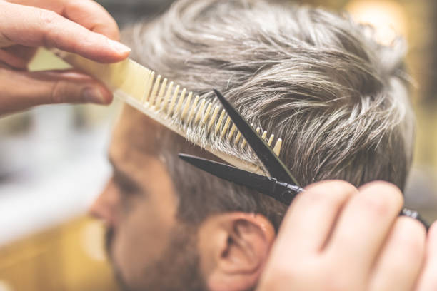 istock Barber cutting and modeling hair with scissors and comb. 1179627497
