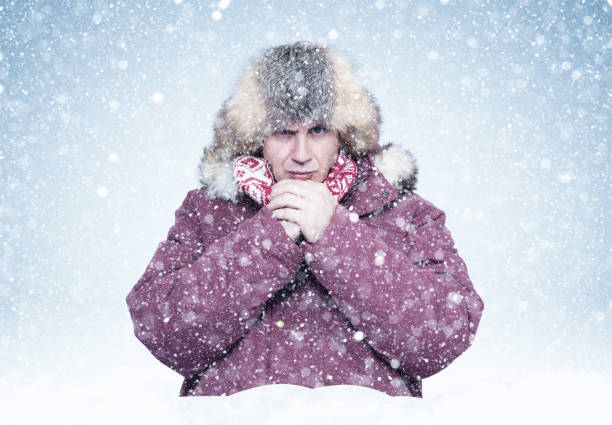istock Frozen man in red winter clothes warms his hands, cold, snow, frost, blizzard 1179628049