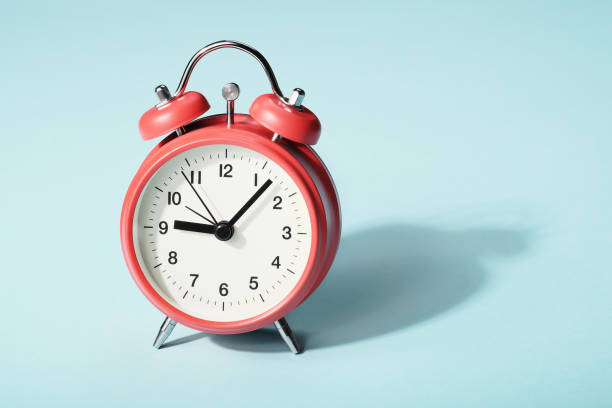 istock Red alarm clock with shadow on blue background. Seven minutes past nine on the clock 1179628982