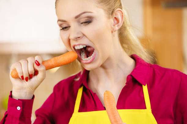 istock Woman holding biting carrot. 1179631419