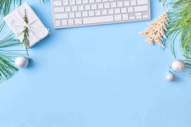 istock Flat lay christmas home office desk with pine branches and keyboard, christmas decorations on a blue background 1179631527