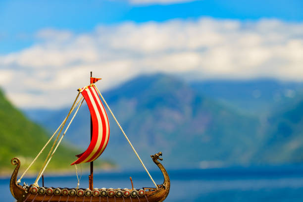 Old wooden viking longboat sails, drakkar boat on fjord shore in Norway. Tourism and traveling concept
