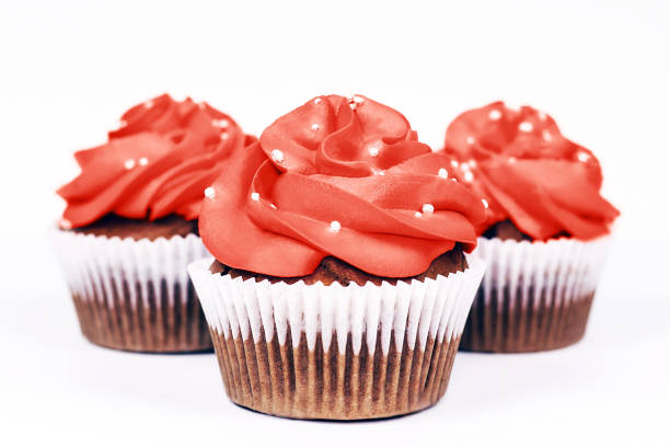 istock Three cupcakes with icing in trendy coral color on isolated white background. Close-up. 1179633205