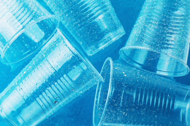istock Empty transparent disposable plastic glasses in drops of water on bright blue background, top view 1179634281