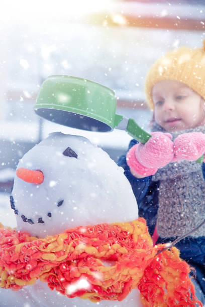 istock Girl Playing with a Snowman 1179636262