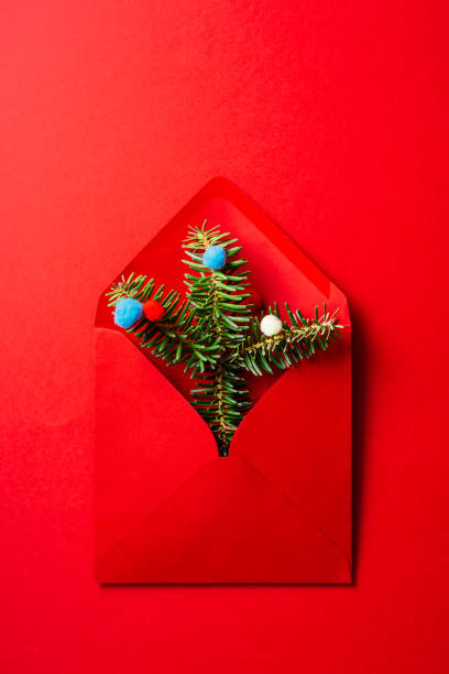 istock Red envelope with fir tree branches and baubles on red background.