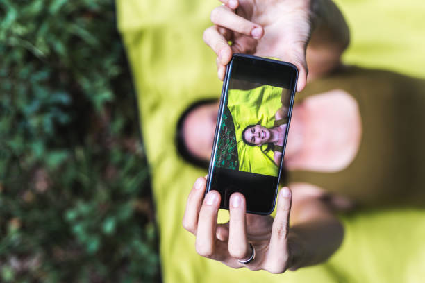 istock Young girl lying down and taking selfie in park 1179639426
