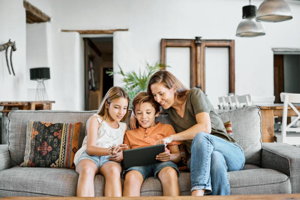 Mother showing digital tablet to children at home stock photo