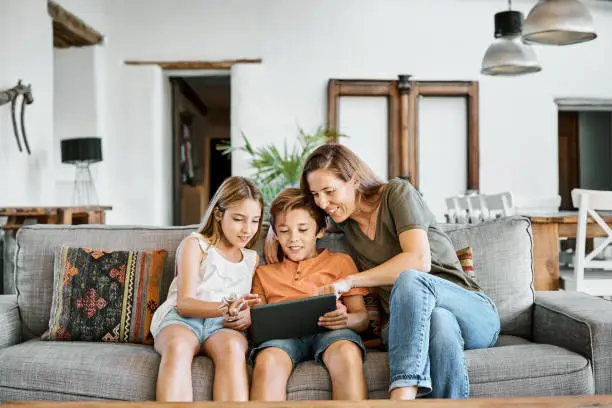 Photo of Mother showing digital tablet to children at home