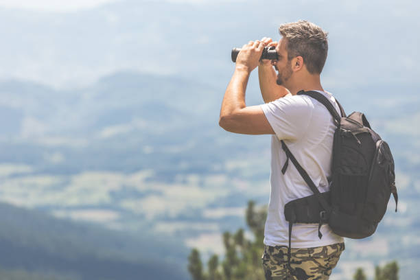 istock Traveler with backpack standing on the top of the mountain and using binoculars 1179641890