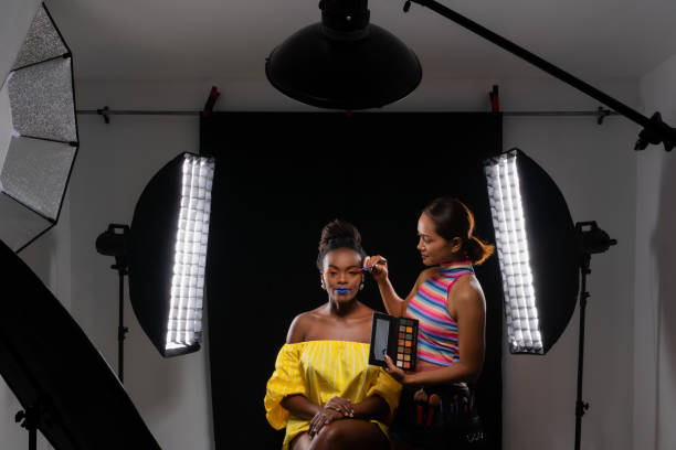 Professional makeup artist working with fashion model. Professional make up artist working with african fashion model at photo studio with many equipment for photography. Light modifier, flash, Beauty Dish, Stripbox, Reflector. makeup artist stock pictures, royalty-free photos & images