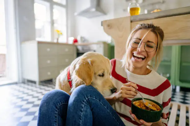 Photo of young woman and her dog in a kitchen at the morning