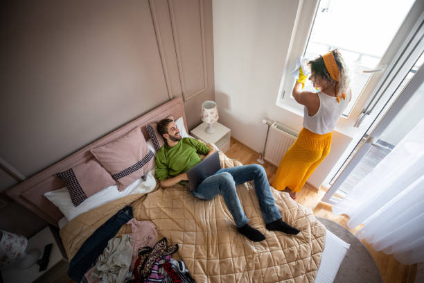 istock Woman cleaning room while husband lying on the bed 1179646542