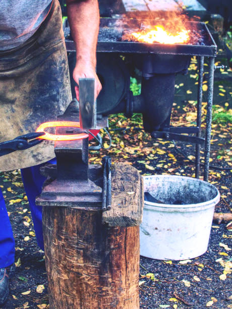 istock Skilled smith man striking a red hot horseshoe on the anvil. 1179647211