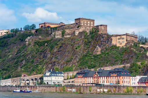 At the top of a cliff we see the Ehrenbreitstein Fortress - a UNESCO World Heritage Site in Upper Middle Rhine Valley - overlooks the east bank of the Rhine River in Koblenz, Germany