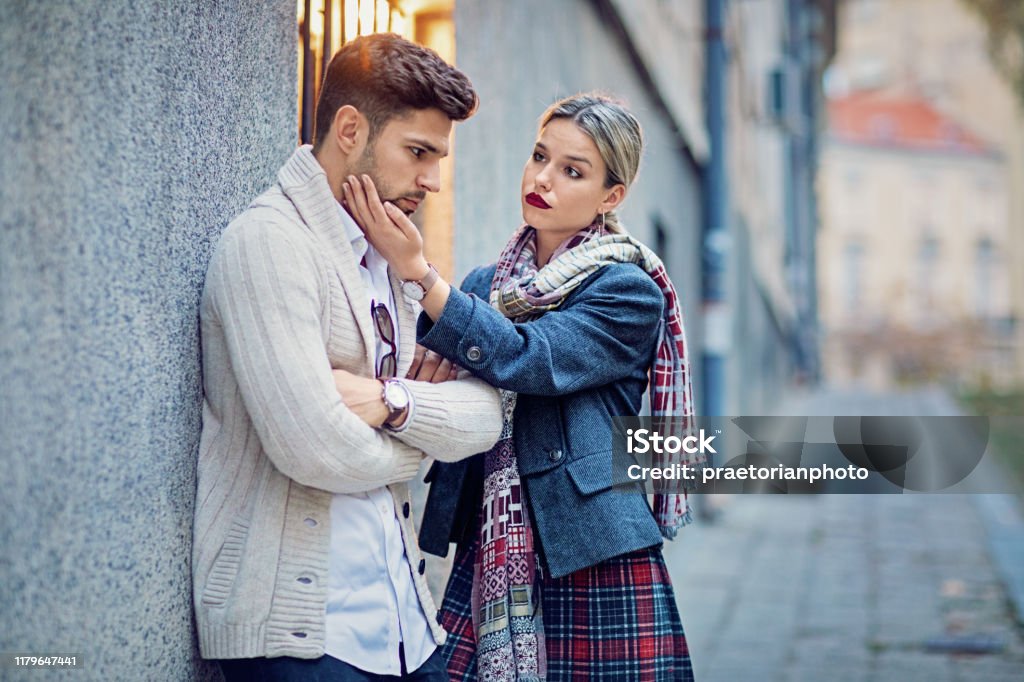 Woman is consoling her sulking boyfriend on the street Envy Stock Photo