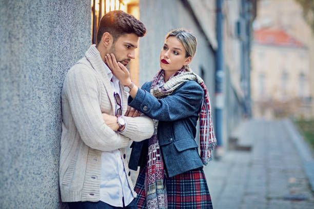 Woman is consoling her sulking boyfriend on the street stock photo