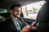 Businessman in the taxi, using a mobile phone