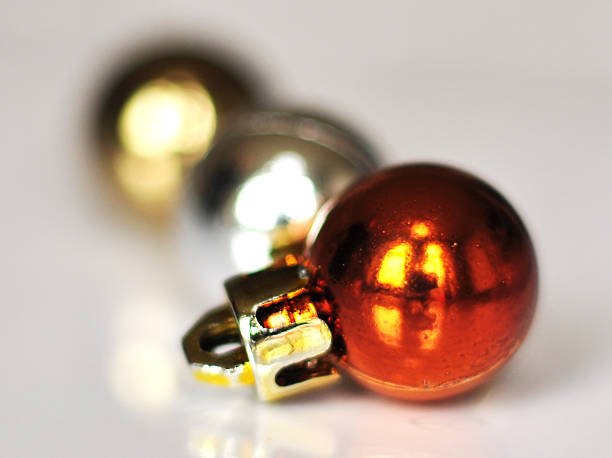 istock Bronze Christmas bauble with silver and gold in the background on reflective white surface 1179649985