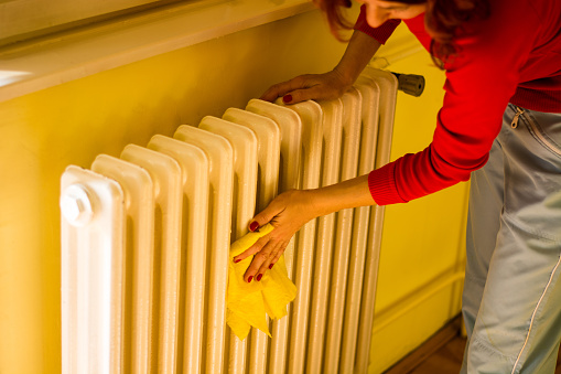 woman clean radiator with cloth for new season