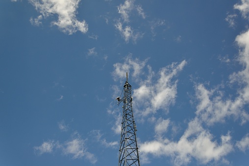 A local weather antenna scans the Chesapeake bay from deal island, Maryland against a blue sky with fluff cumulus clouds