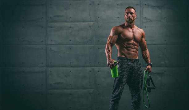 guapo sin atltico hombres sosteniendo proteína bebida botella y bandas de resistencia - body building exercises audio fotografías e imágenes de stock