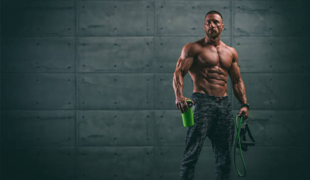 Handsome Athletic Men Holding Protein Drink Bottle and Resistance Bands stock photo