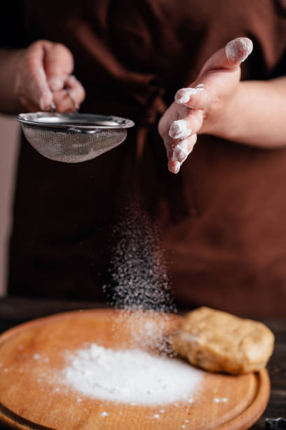 istock confectioner sprinkling flour on gingerbread dough 1179655824