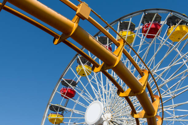 istock Colorful ferris wheel above a roller coaster track under a blue sky 1179661016