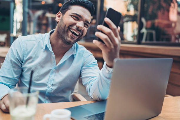 istock Young man with a cell phone and laptop in cafe 1179664272