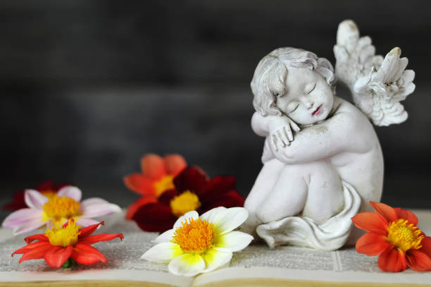 istock Guardian angel and dahlia flowers on old book 1179665864