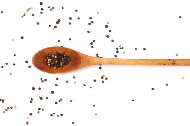Wooden spoon and dried pepper seeds on white background