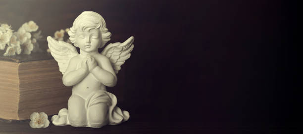 istock Guardian angel, spring flowers and old book on dark background with copy space 1179670165